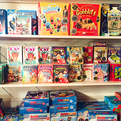 Three shelves filled with a variety of board games.