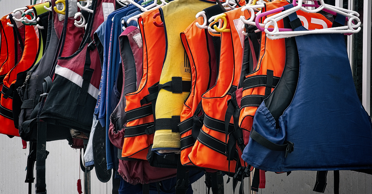 A group of life vests on hangers on a coat rack