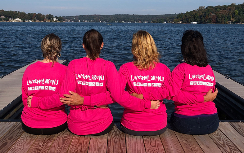 4 women on the docks with breast cancer awareness long-sleeved tees.